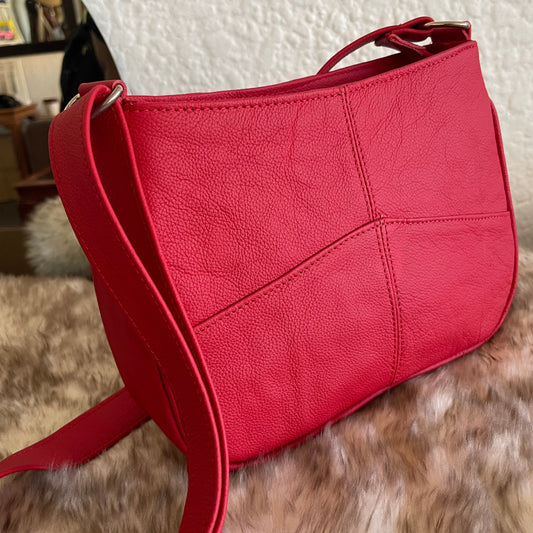 Red genuinely leather bag on top of sheepskin 
