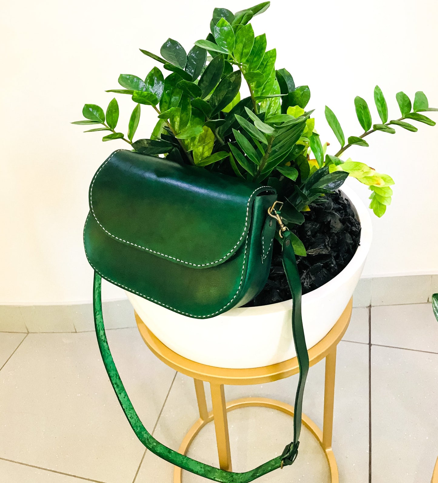saddle stitched genuine leather green bag on a flower pot