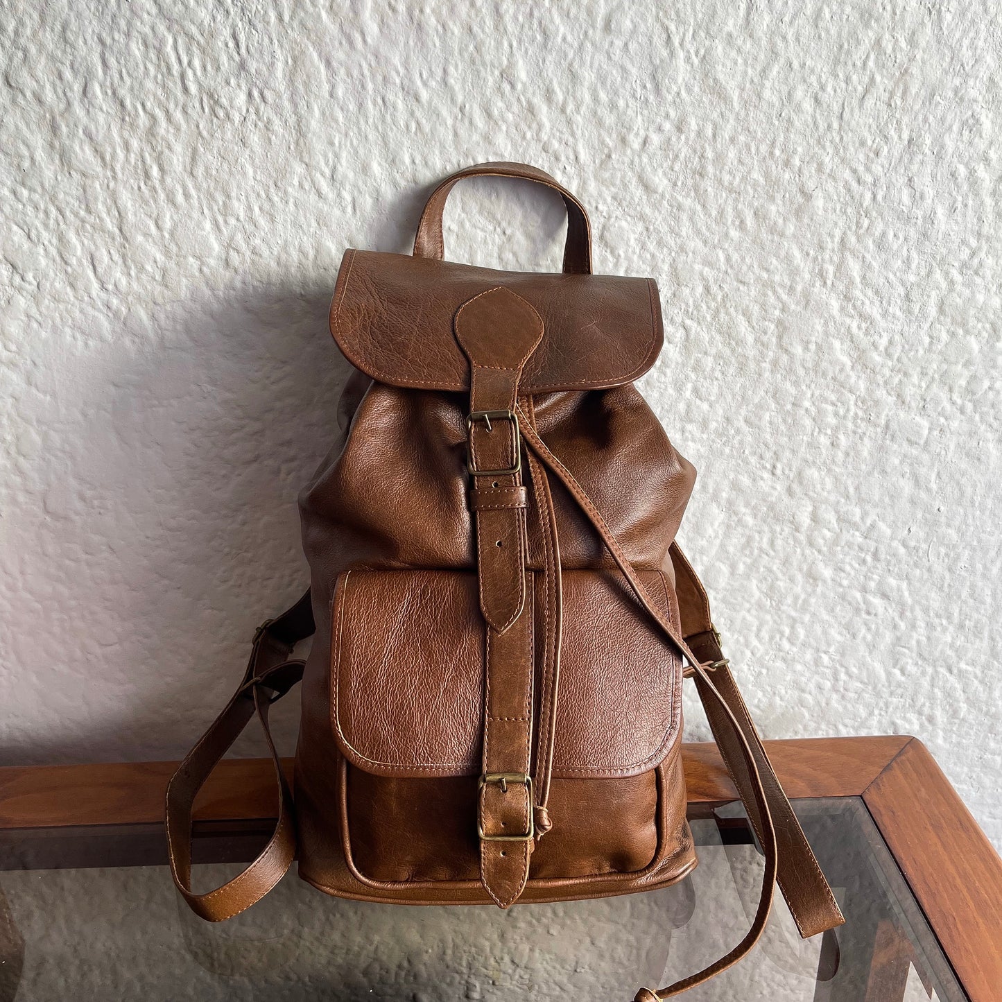 Brown leather backpack on a white textured wall