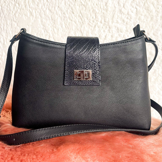 Black leather handbag with a strap on a textured surface