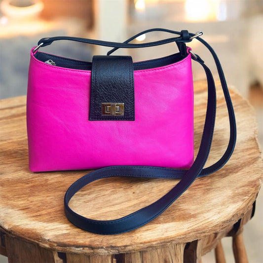 Pink handbag with black strap on a wooden surface