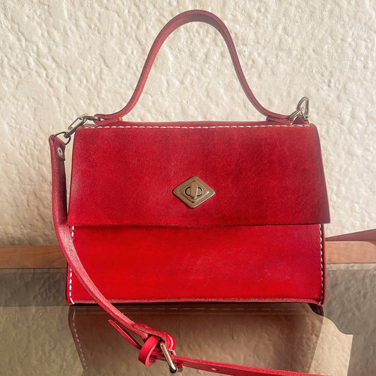 Red handbag with a gold clasp on a textured surface