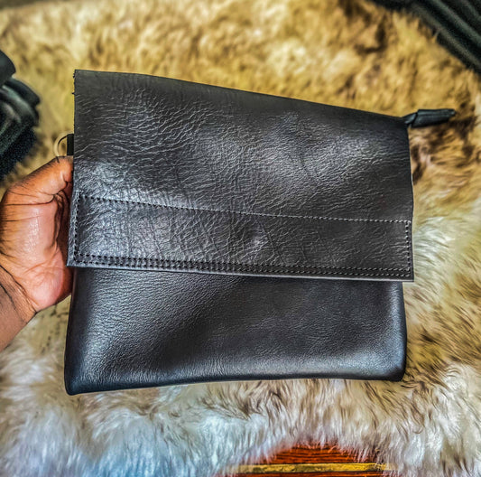 a black genuine leather sling bag with a flap 
