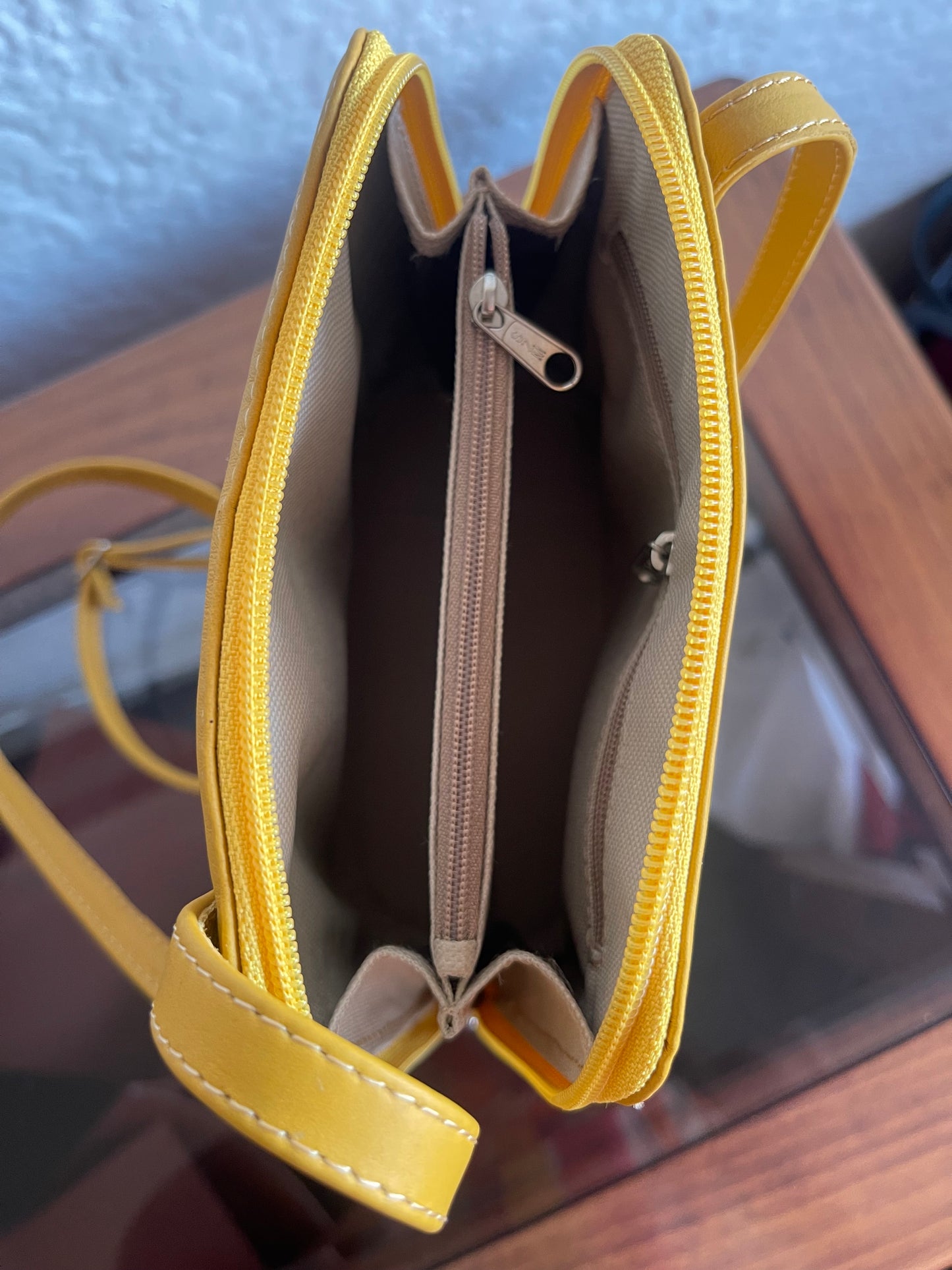 Yellow handbag with a visible zipper on a reflective surface