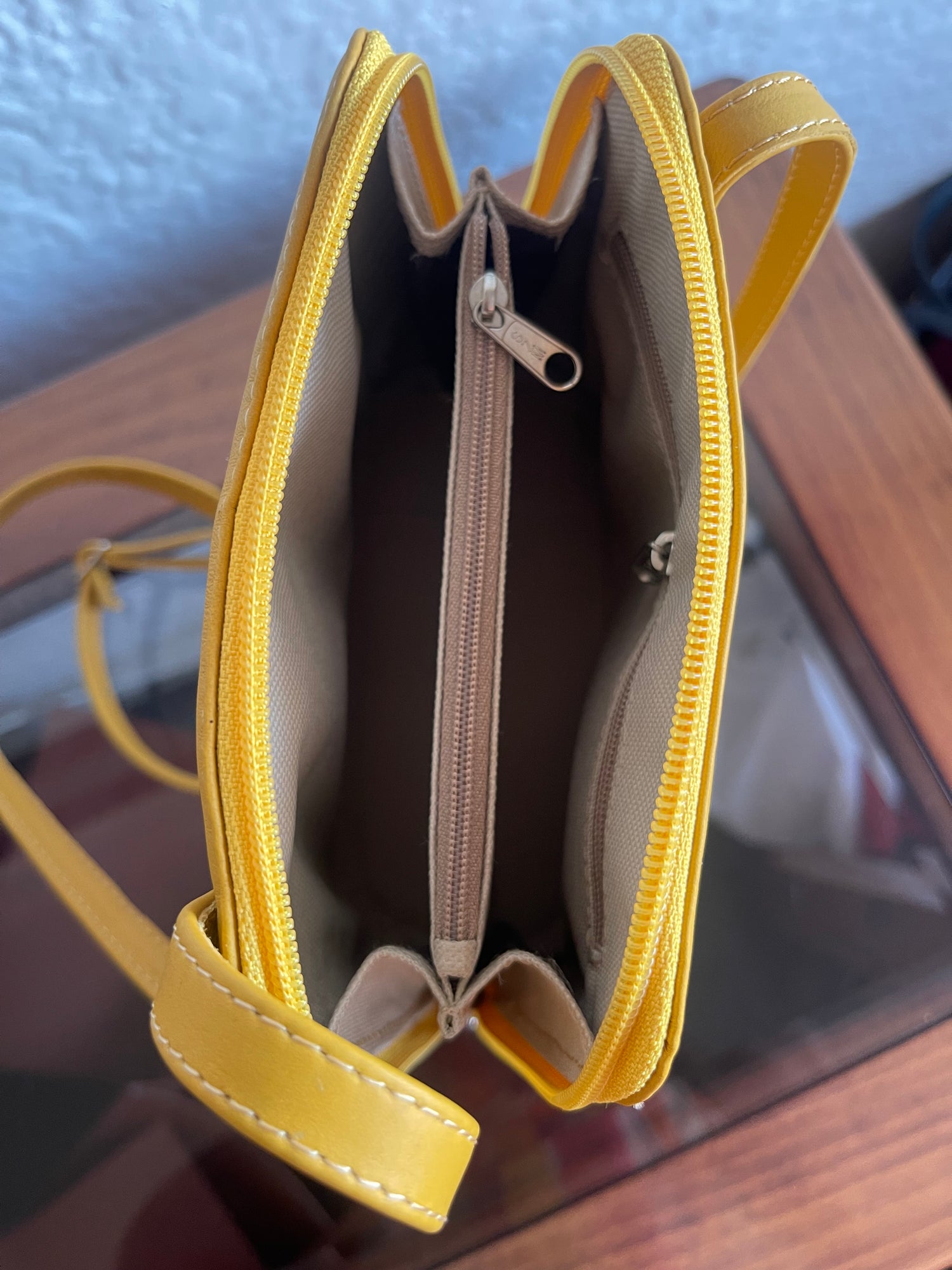 Yellow handbag with a visible zipper on a reflective surface