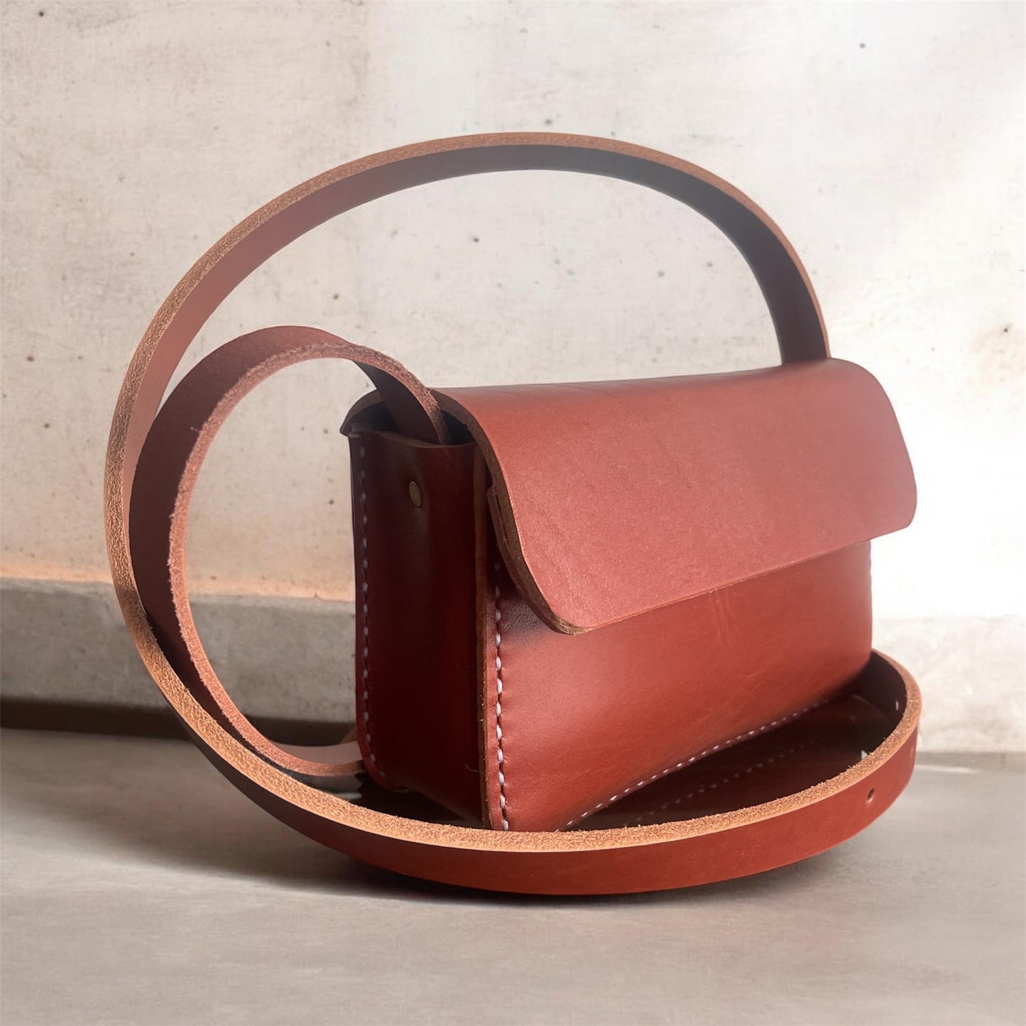 Brown leather handbag with a strap on a light background