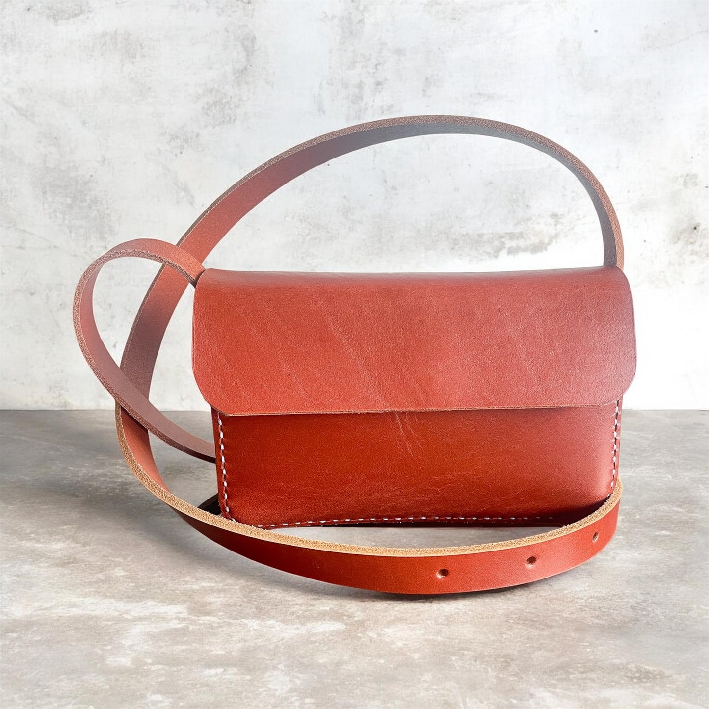 Red leather handbag on a gray surface with a light gray background