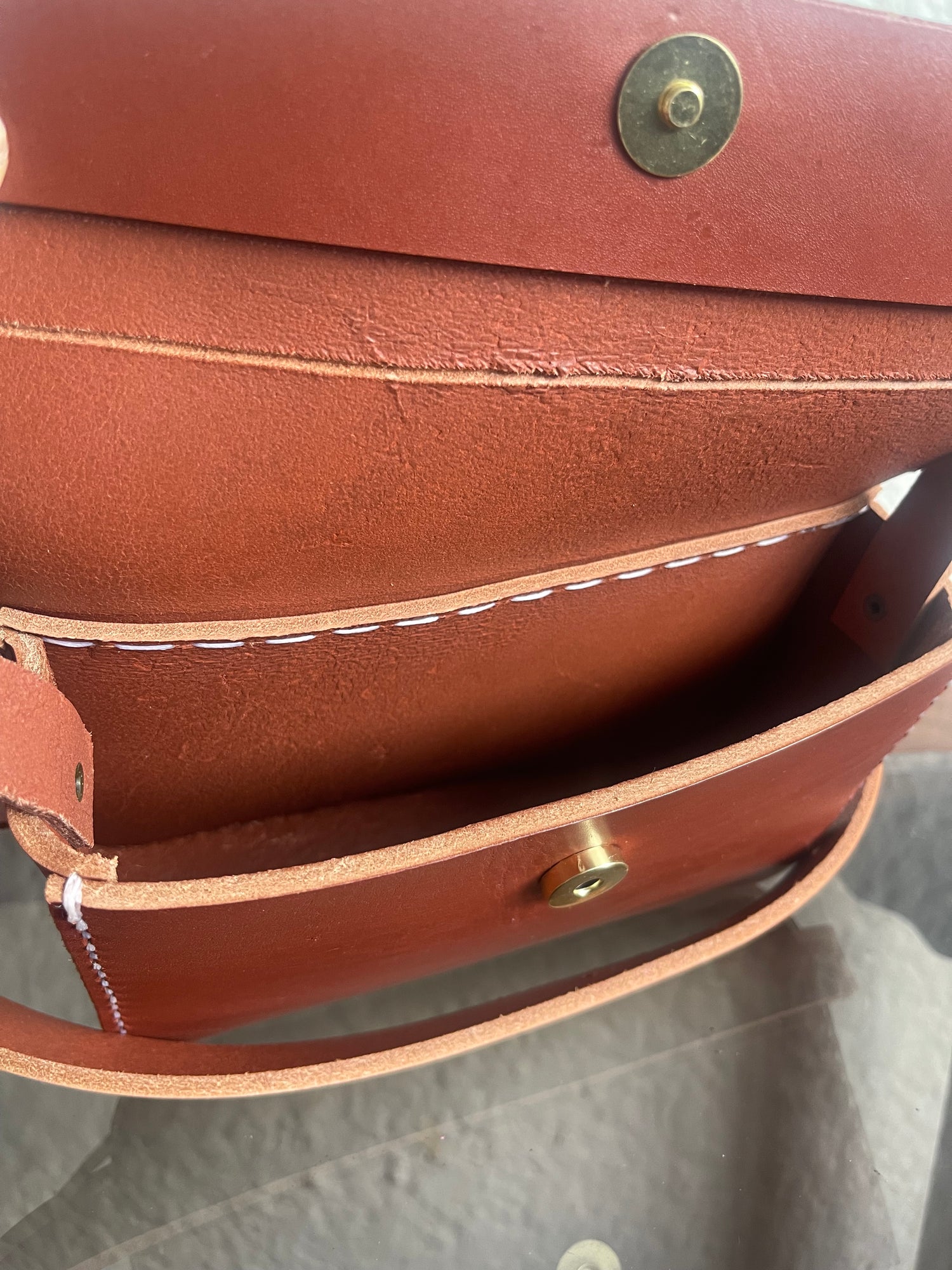Close-up of a brown leather bag with gold studs on a gray surface