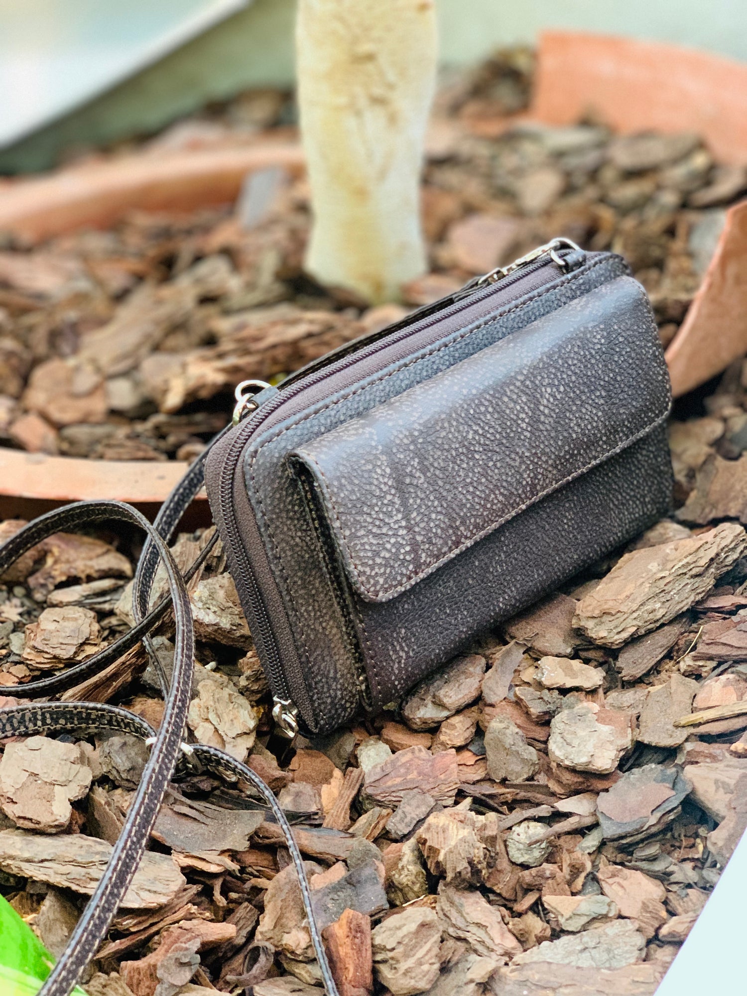 Black leather wallet with a strap on a textured surface