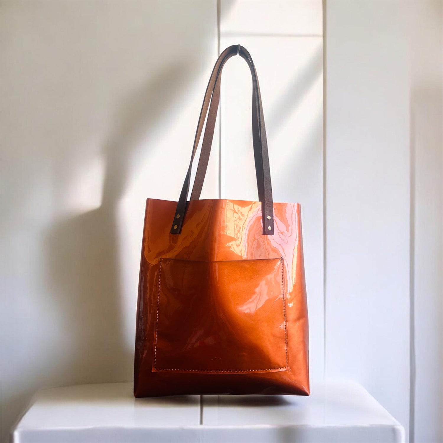 Metalic Brown tote bag with black handles on a white surface