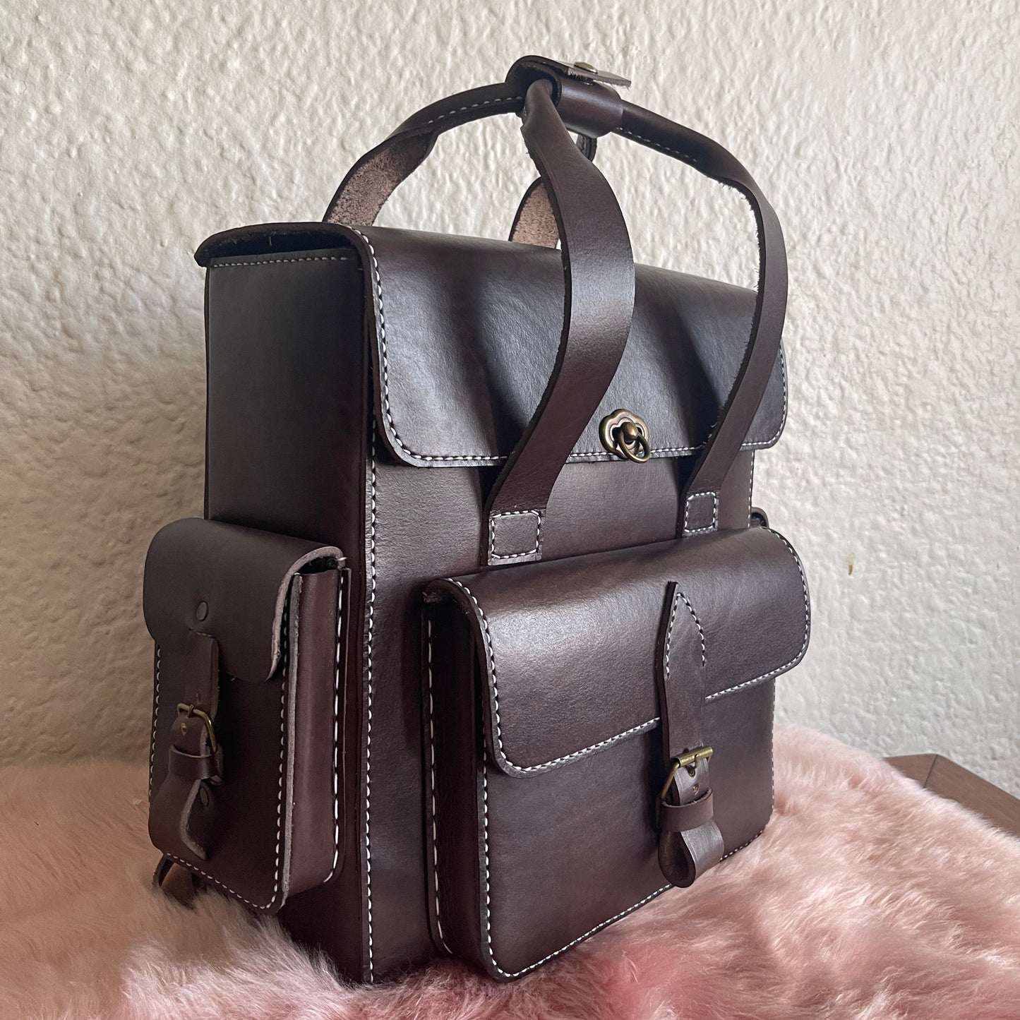 Brown leather satchel bag on a textured surface