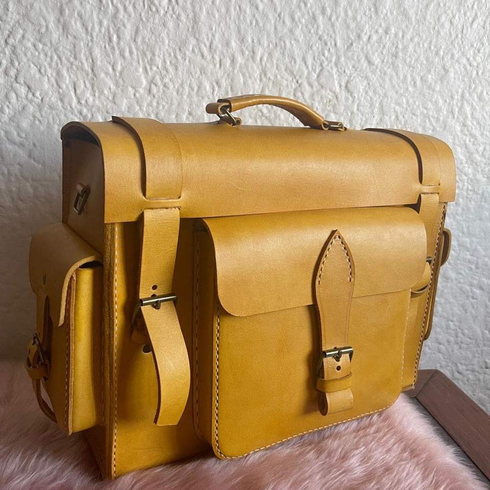 Yellow leather satchel bag on a textured surface with a white wall background