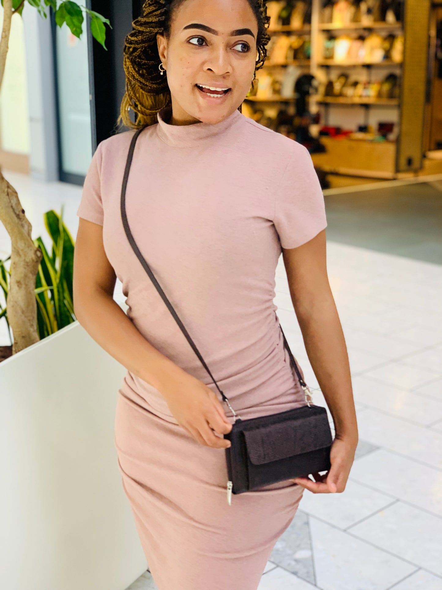 Woman in a pink dress holding a black handbag in an indoor setting