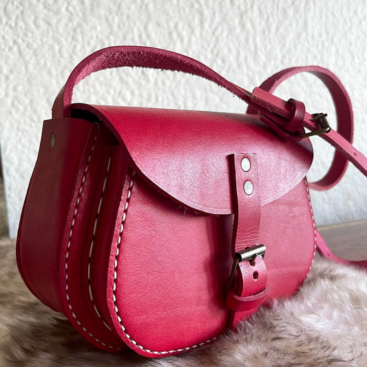 saddle stitched genuine leather red bag on a sheepskin rug