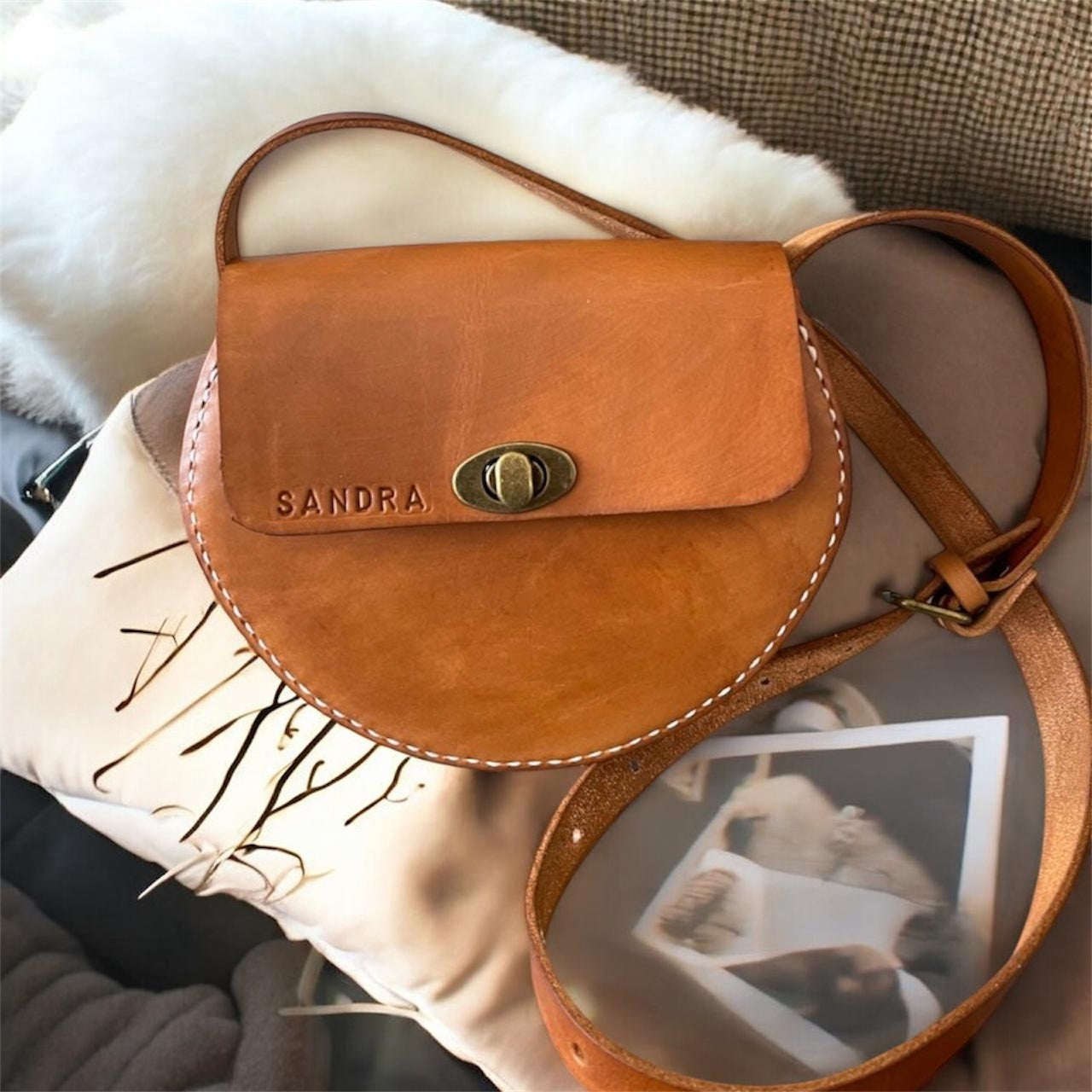 Brown leather bag with 'SANDRA' branding on a textured surface