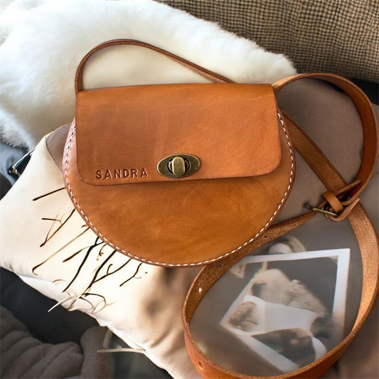 Brown leather bag with 'SANDRA' branding on a textured surface