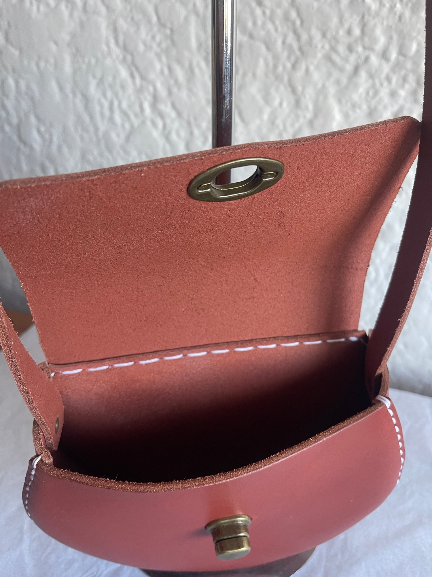 Close-up of a brown leather bag with gold hardware on a white background