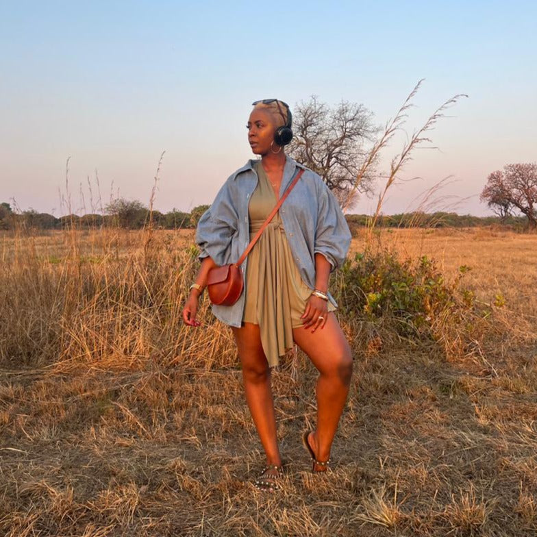 woman in a field carrying a genuine saddle stitched brown genuine leather bag