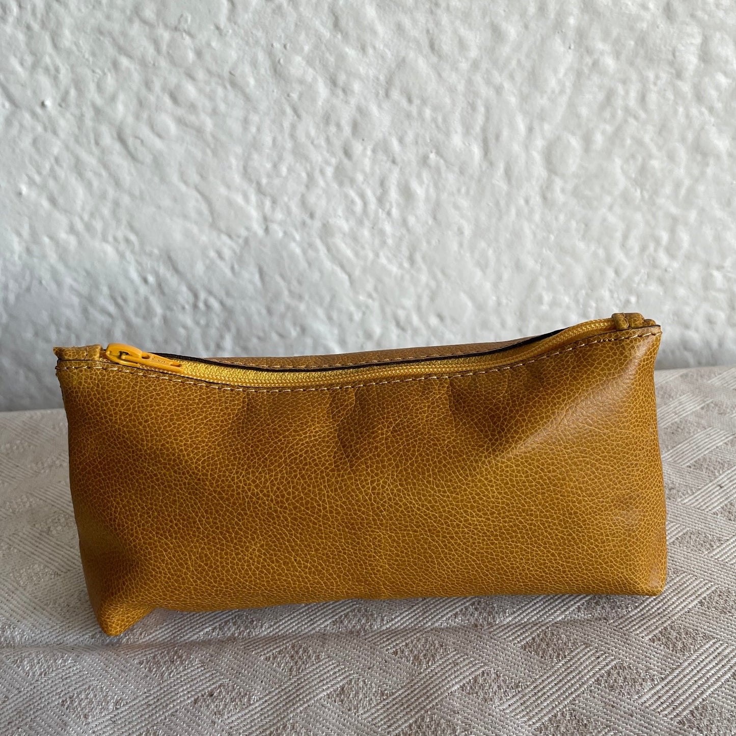 Brown leather pouch on a textured white surface