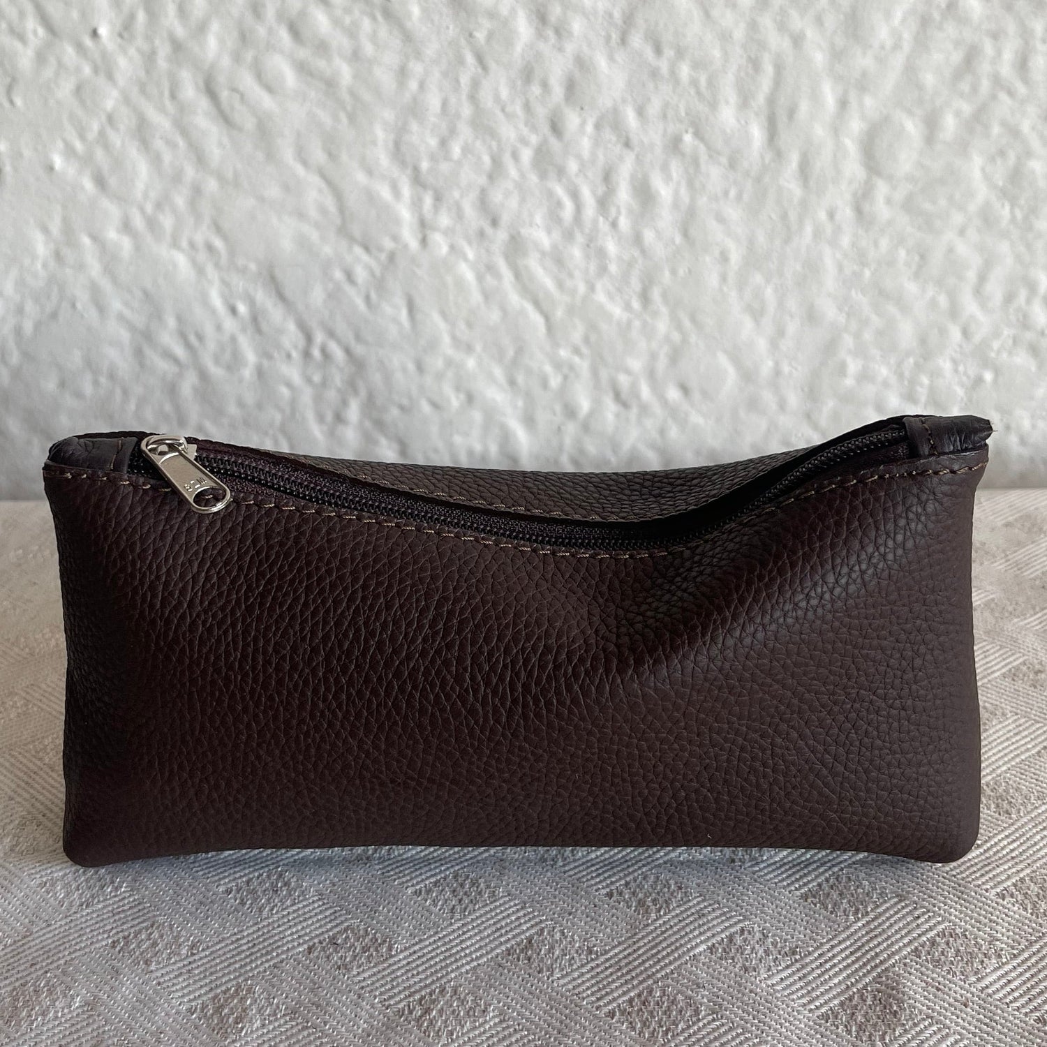 Brown leather pouch on a textured white and gray surface