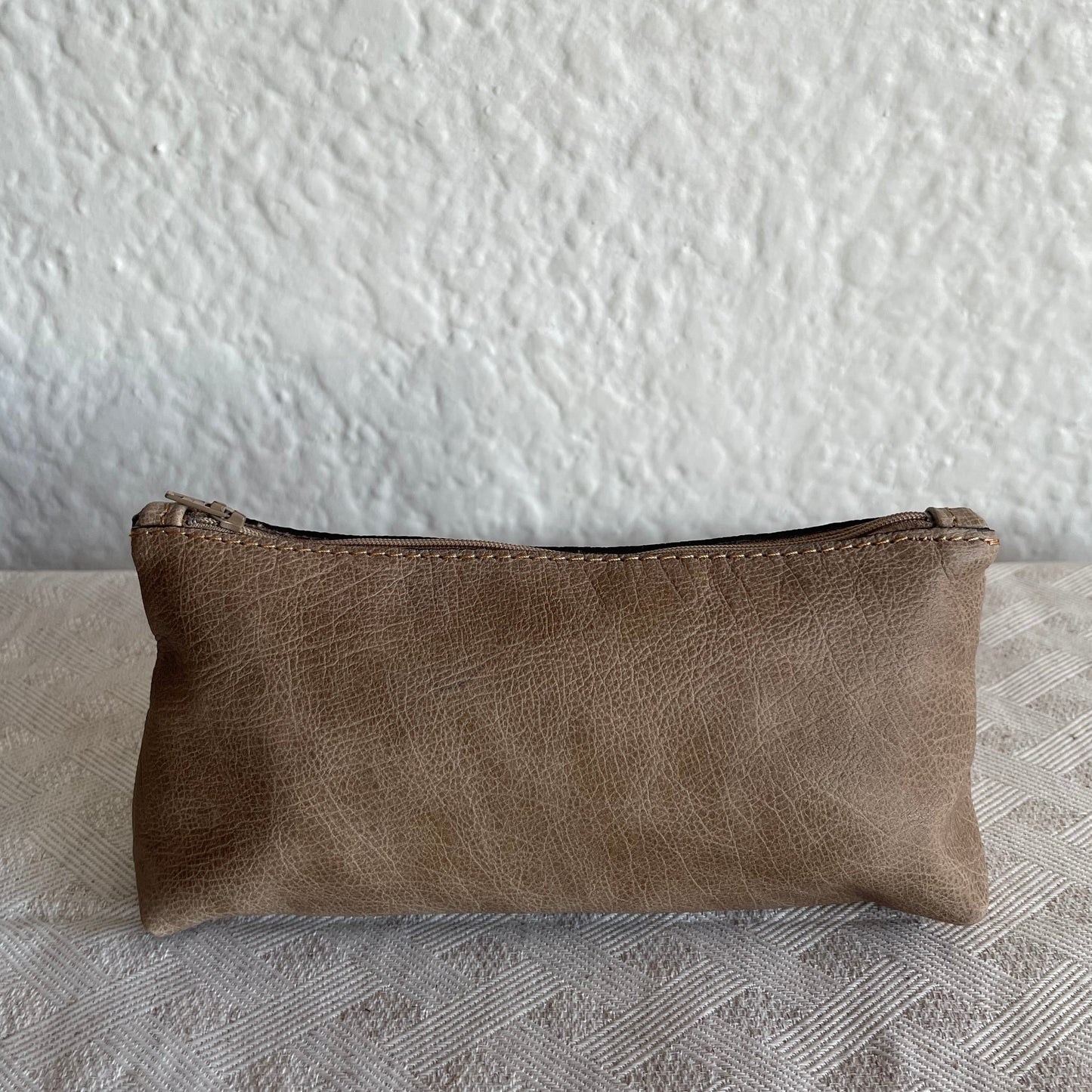 Brown genuine leather pouch on a textured white surface