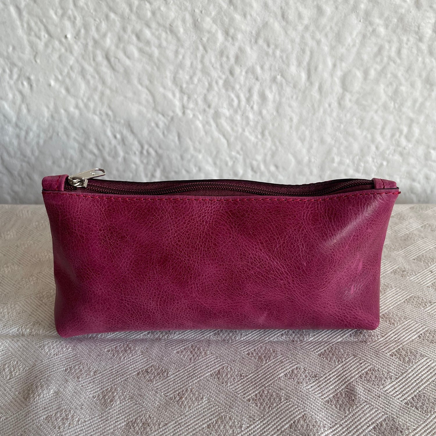 Purple genuine leather pouch on a textured white surface