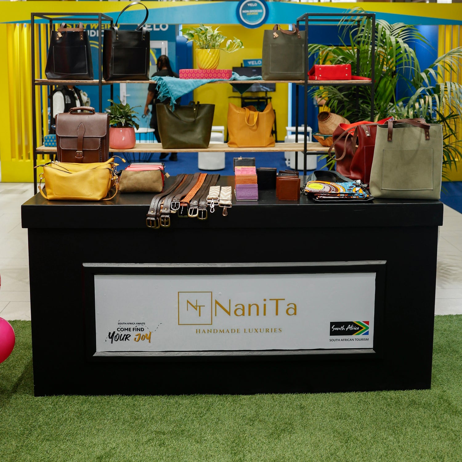Display of handbags and accessories with NaniTa branding at an event.
