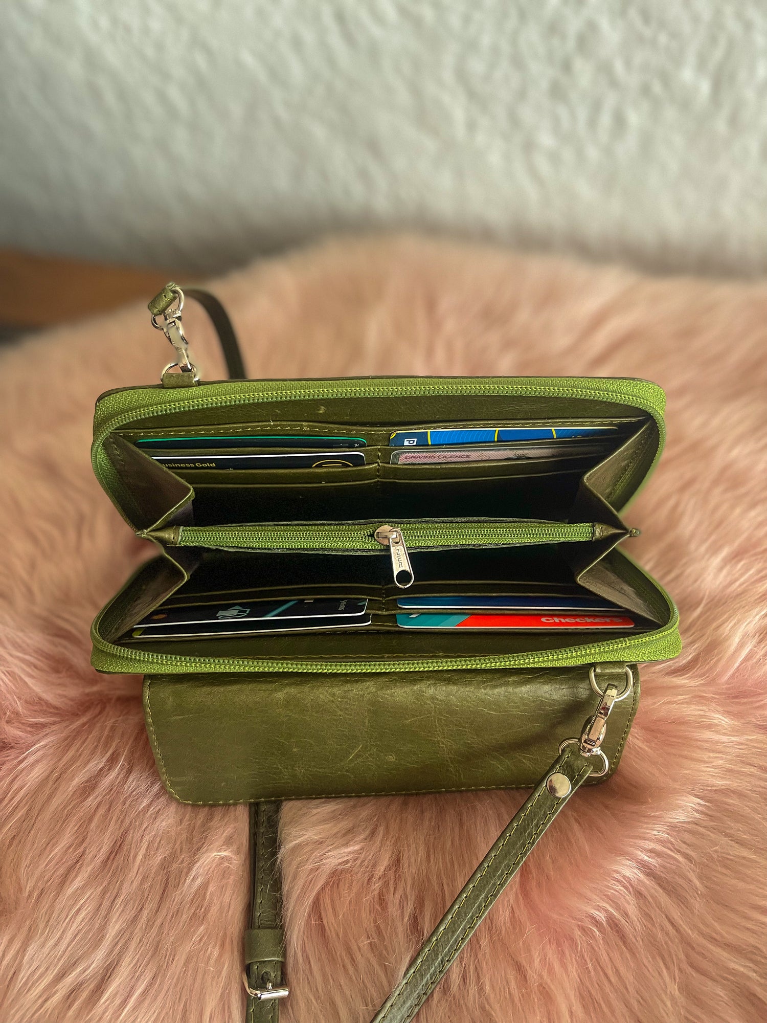 Green wallet with card slots on a pink fluffy surface