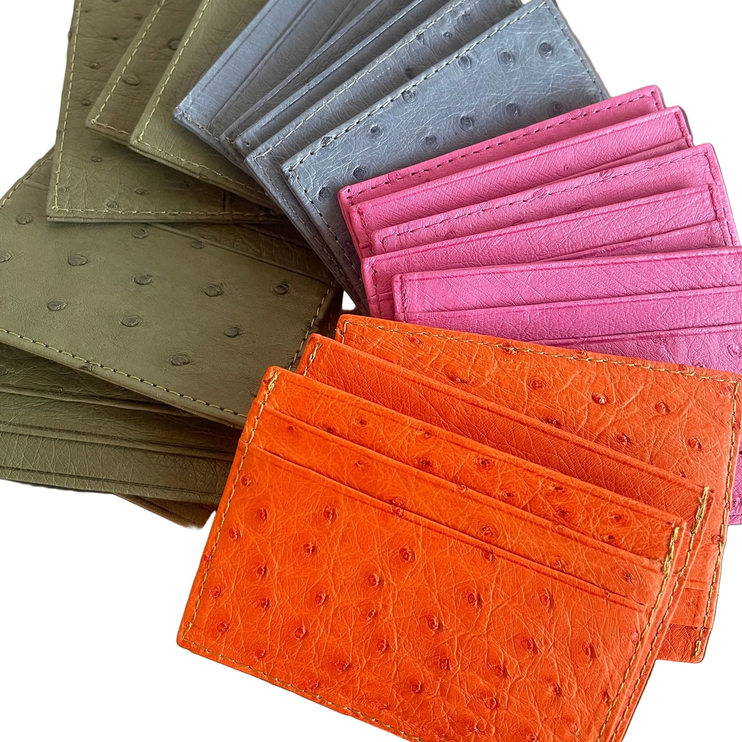 Collection of ostrich leather card holders in various colors on a wooden surface.