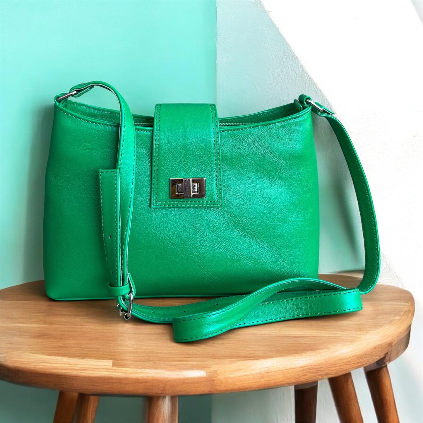 Green handbag on a wooden stool with a light green wall background