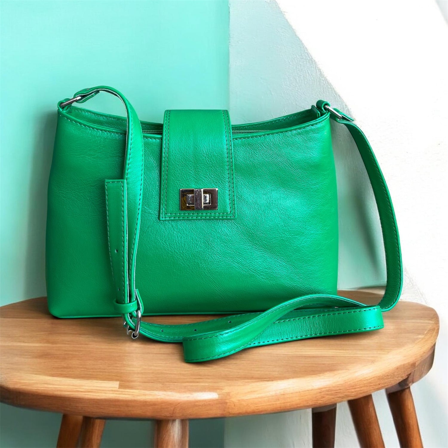 Green handbag on a wooden stool with a light green wall background
