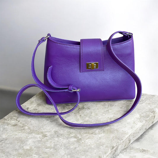 Purple handbag with a gold clasp on a marble surface
