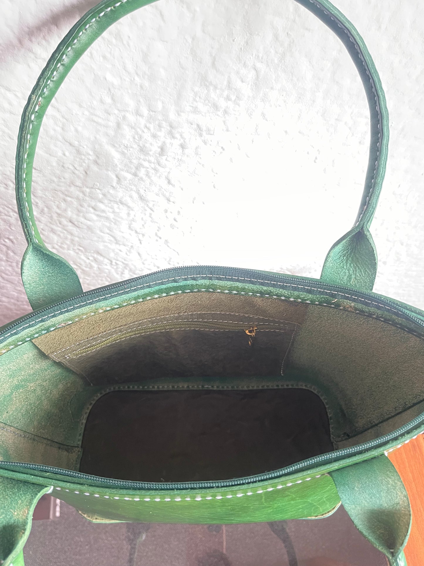 Green leather bag with a textured white background