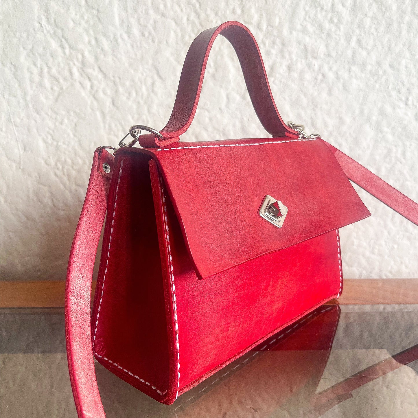 Red handbag with a silver clasp on a textured surface