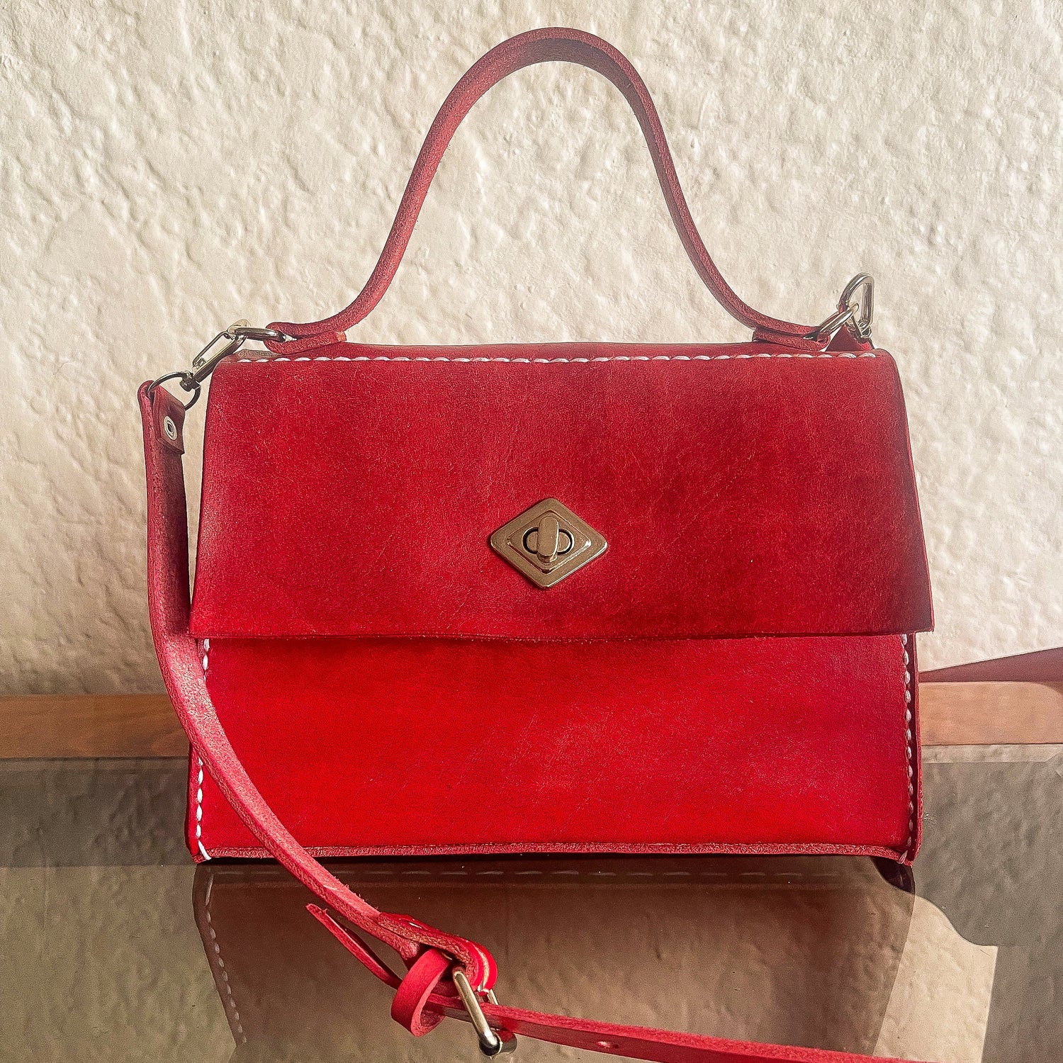 Red handbag with a gold clasp on a textured surface